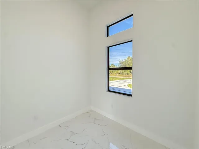 Spare room with marble look tiles and baseboards