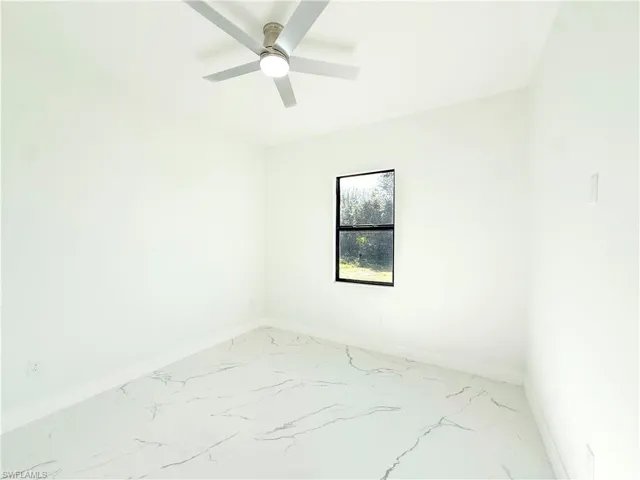 Unfurnished room with light marble finish flooring and ceiling fan