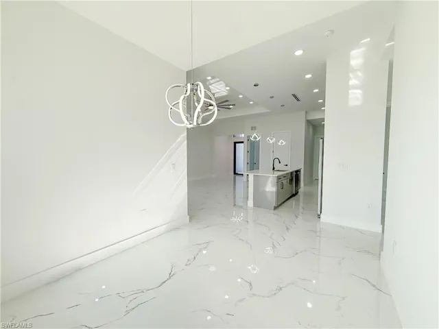 Unfurnished dining area with recessed lighting, a chandelier, and light marble finish floors