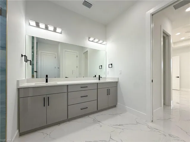 Bathroom featuring double vanity, light marble finish flooring, and recessed lighting