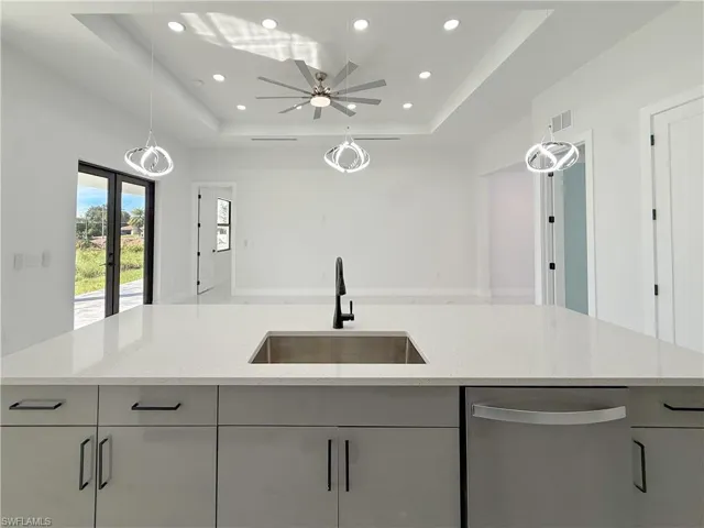 Kitchen with hanging light fixtures, recessed lighting, dishwasher, light stone countertops, and french doors