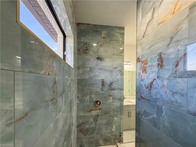 Full bath with a marble finish shower, vanity, and tile walls