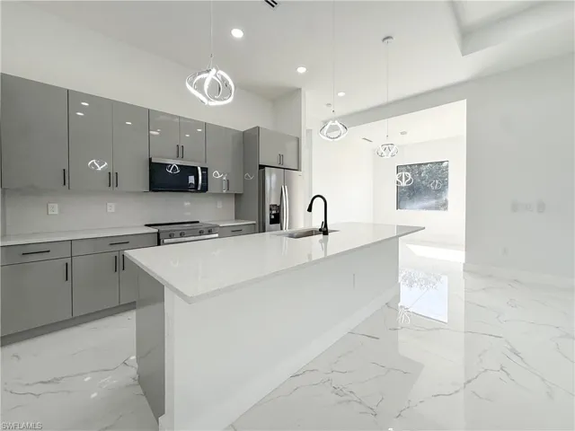 Kitchen featuring gray cabinetry, decorative light fixtures, a kitchen island with sink, appliances with stainless steel finishes, and recessed lighting