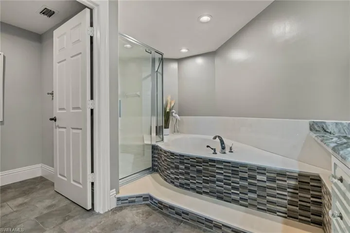 Bathroom with a shower stall, a bath, and recessed lighting