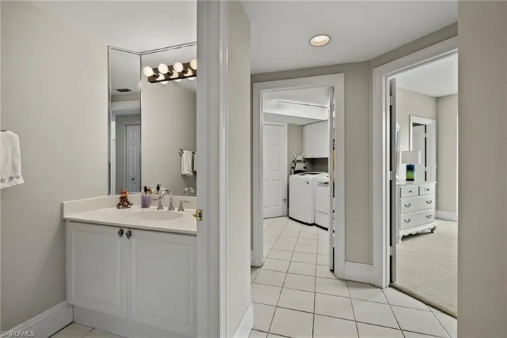 Bathroom with light tile patterned floors, vanity, washer and clothes dryer, light colored carpet, and recessed lighting