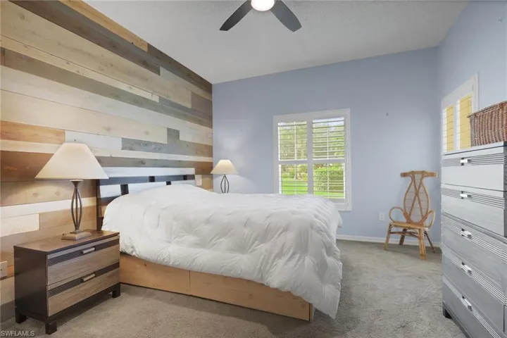 Accent wall featuring multi-tonal wood planking, wall-to-wall carpeting, and plantation shutters