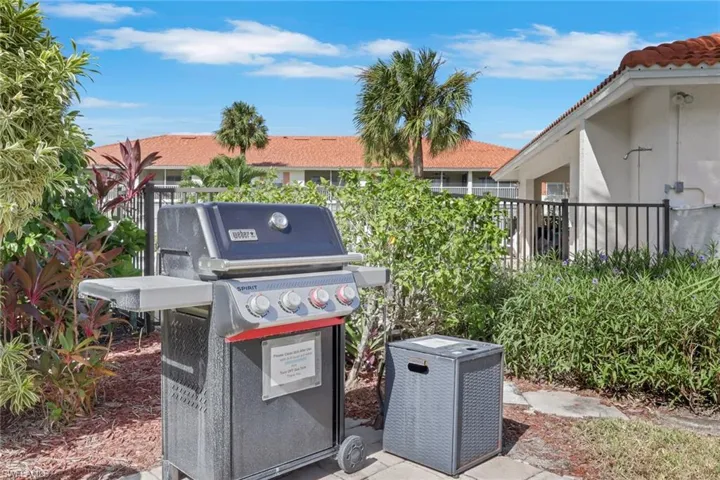 Outdoor patio area featuring stone paver flooring, black metal perimeter fencing, and mature landscaping