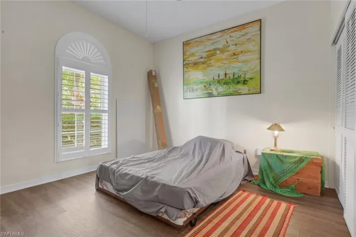 Arched window with decorative fanlight, wood-finish flooring, and louvered closet doors