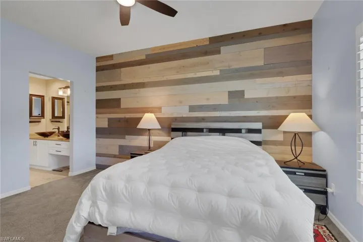 Multi-tonal wood plank accent wall, carpeted flooring, and a ceiling-mounted light fixture