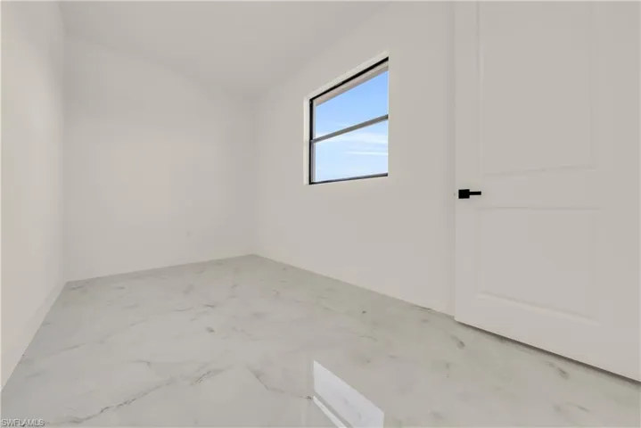 Spare room with light marble finish flooring and lofted ceiling