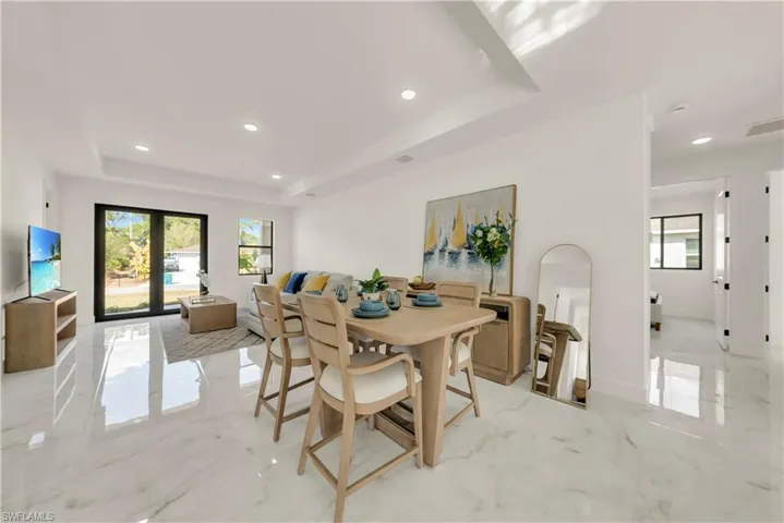 Dining space with recessed lighting, light marble finish flooring, and a tray ceiling
