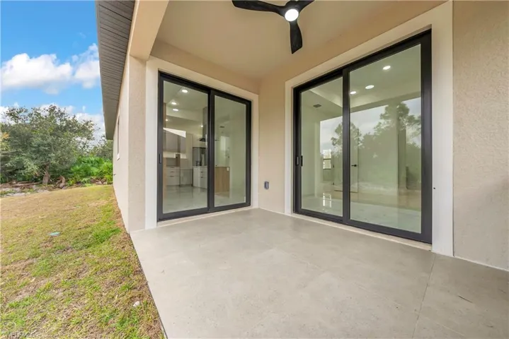 View of exterior entry with ceiling fan, a patio area, and stucco siding