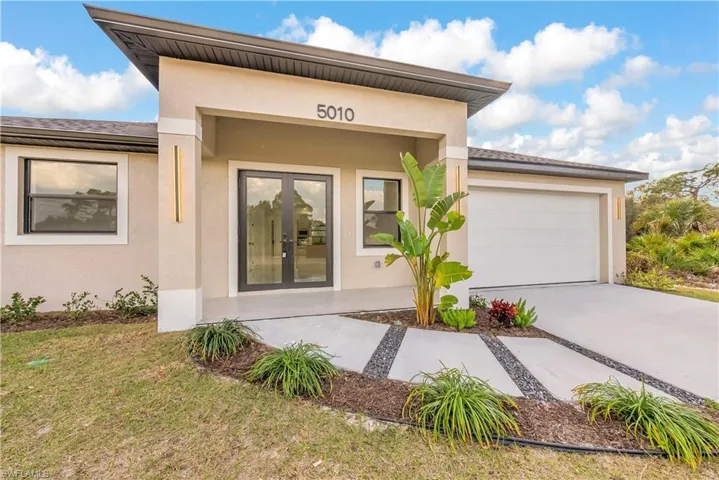 Entrance to property with french doors, stucco siding, and concrete driveway