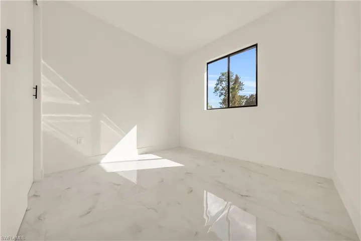 Spare room with marble finish flooring and lofted ceiling