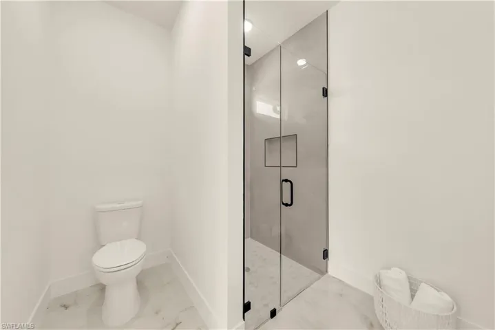 Full bathroom featuring a marble finish shower and marble look tile flooring
