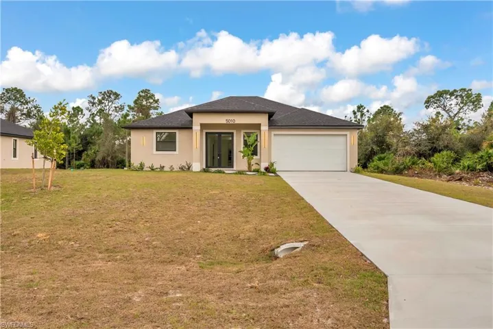 Prairie-style house featuring concrete driveway, a front lawn, stucco siding, and an attached garage