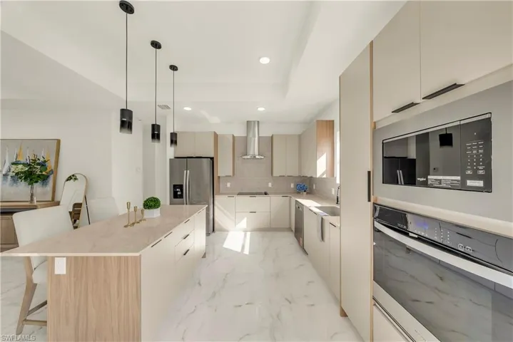 Kitchen featuring a breakfast bar, stainless steel appliances, a kitchen island, modern cabinets, and pendant lighting