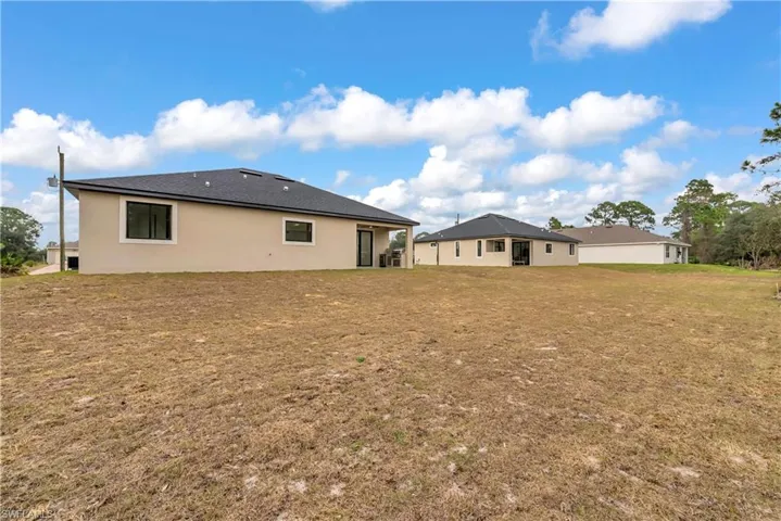 Rear view of property with stucco siding, a yard, and a patio area