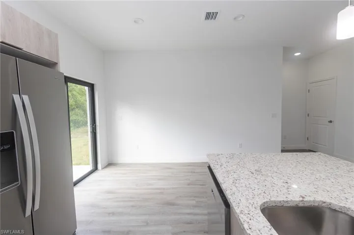 Kitchen with light vinyl  flooring, modern cabinets, light stone counters, and stainless steel appliances