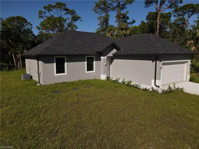 Ranch-style house with stucco siding, a front lawn, cooling unit, roof with shingles, and an attached garage