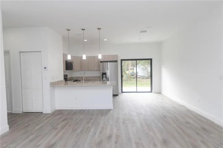 Kitchen featuring light wood finished floors, stainless steel appliances, a sink, and open floor plan