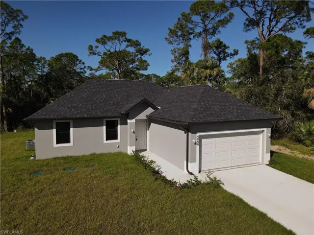 Ranch-style house featuring stucco siding, an attached garage, roof with shingles, and a front lawn