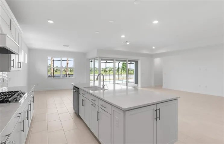 Kitchen featuring sink, white cabinetry, a healthy amount of sunlight, and a center island with sink