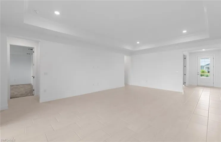 Unfurnished living room with a tray ceiling and light tile patterned floors