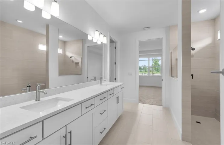 Bathroom with tiled shower, tile patterned floors, and dual bowl vanity
