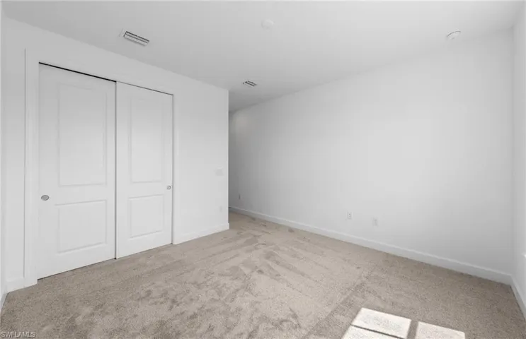 Unfurnished bedroom with a closet and light colored carpet