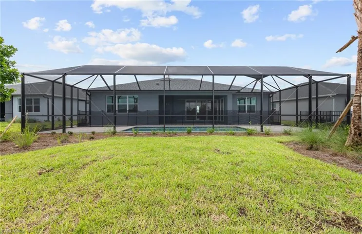Rear view of property with glass enclosure and a lawn