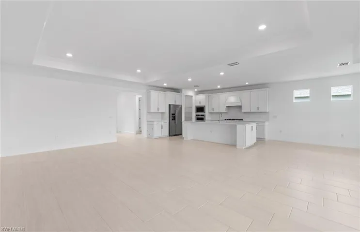 Unfurnished living room with sink and a raised ceiling