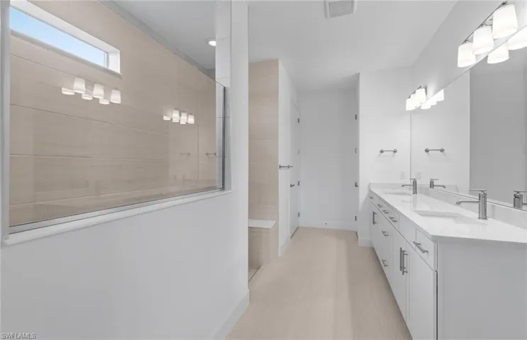 Bathroom featuring tile patterned floors, double sink vanity, and a tile shower