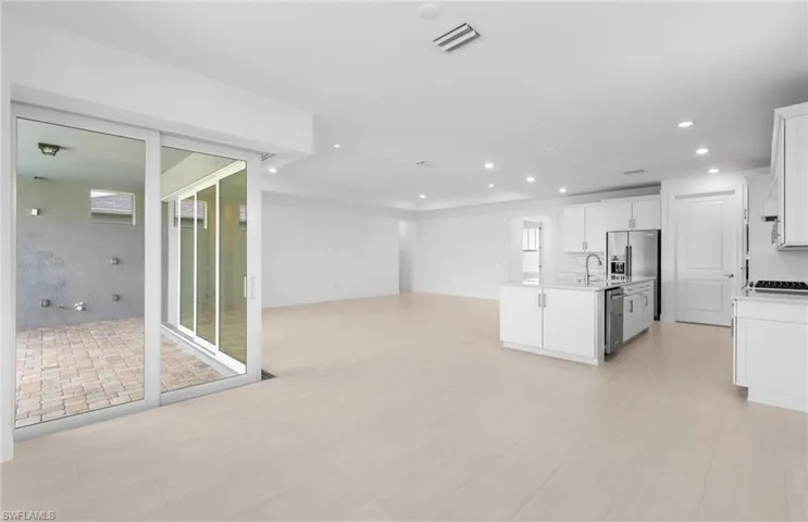 Kitchen featuring sink, appliances with stainless steel finishes, white cabinets, and a center island with sink