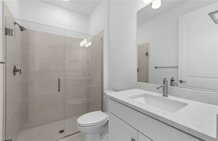 Bathroom featuring vanity, a shower with shower door, and toilet