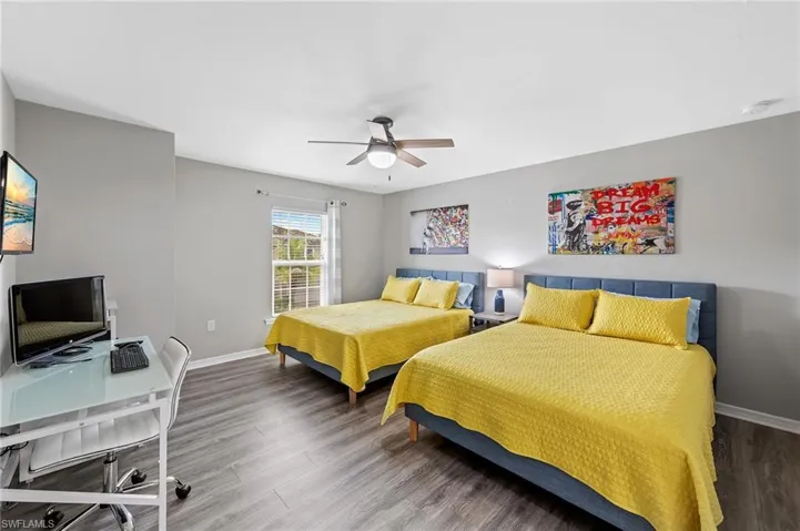 Bedroom featuring an office area, wood finished floors, and a ceiling fan