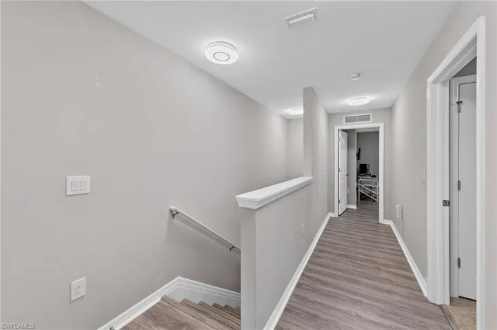 Hall with an upstairs landing and light wood-style floors