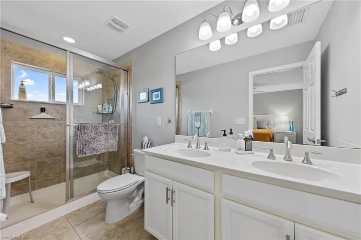 Bathroom featuring double vanity, a stall shower, light tile patterned flooring, and ensuite bathroom