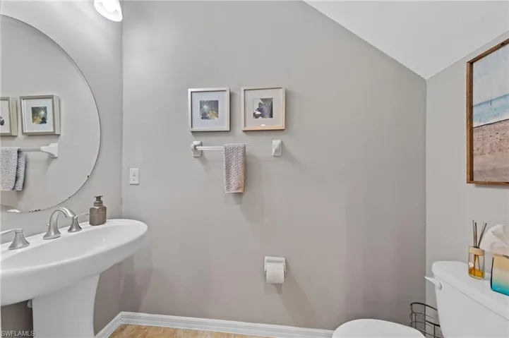 Half bathroom featuring toilet and lofted ceiling