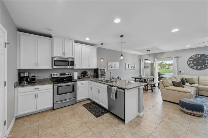 Kitchen with appliances with stainless steel finishes, white cabinets, open floor plan, recessed lighting, and dark stone counters