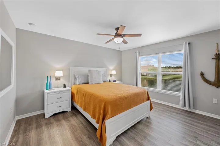 Bedroom featuring wood finished floors, ceiling fan, and a water view