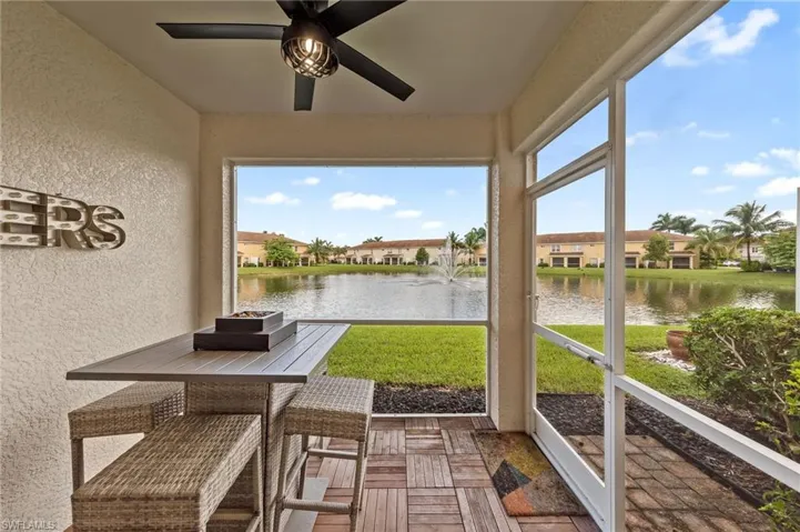 Sunroom with a water view, a ceiling fan, and a residential view