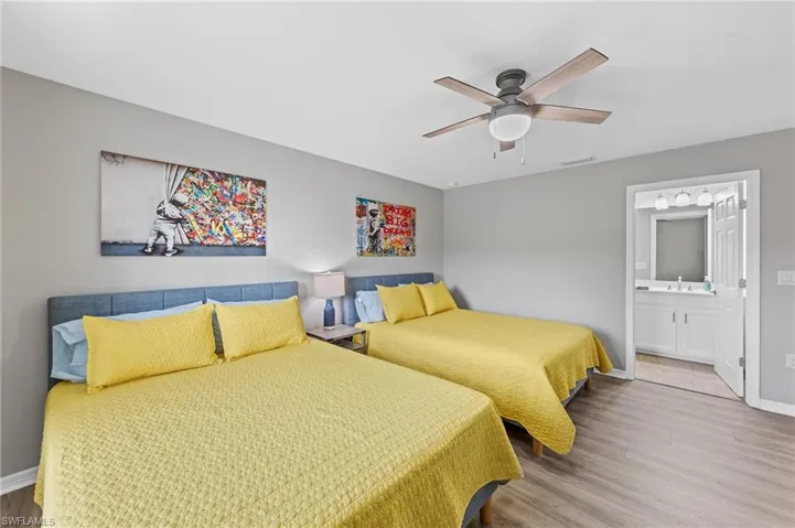 Bedroom featuring wood finished floors, ceiling fan, and ensuite bath