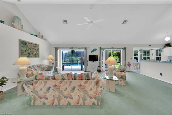 Living area with carpet, high vaulted ceiling, and ceiling fan
