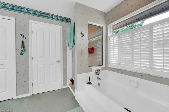Bathroom with wallpapered walls, a garden tub, a stall shower, and carpet