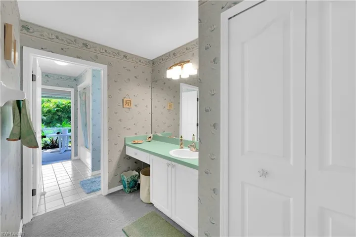 Full bath with wallpapered walls, light tile patterned floors, vanity, and light colored carpet