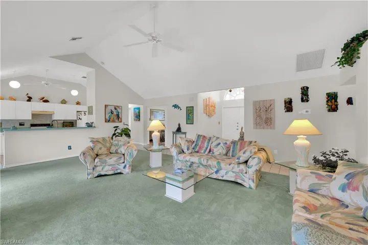 Living room featuring high vaulted ceiling, carpet floors, and ceiling fan
