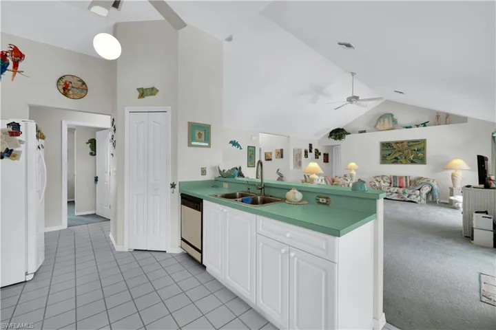 Kitchen with a ceiling fan, high vaulted ceiling, freestanding refrigerator, open floor plan, and hanging light fixtures