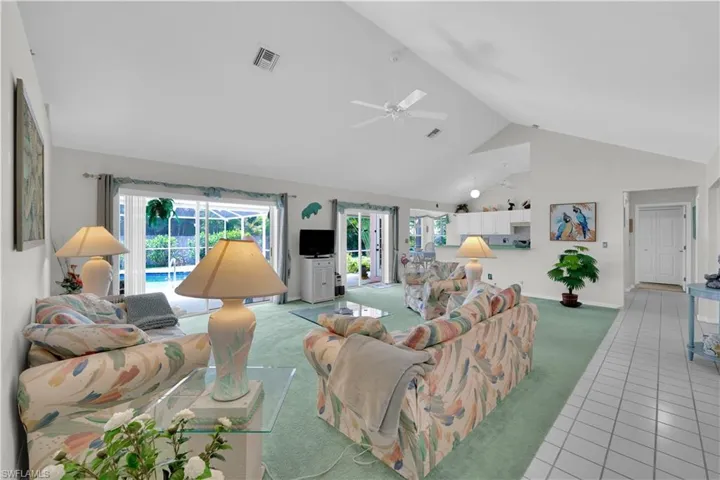 Tiled living room with high vaulted ceiling, carpet floors, and ceiling fan
