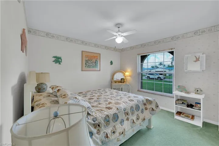 Carpeted bedroom featuring a ceiling fan and wallpapered walls